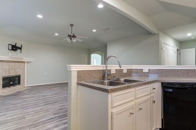 kitchen featuring sink, white cabinetry, light hardwood / wood-style flooring, dishwasher, and a fireplace