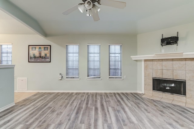 unfurnished living room with lofted ceiling, a healthy amount of sunlight, a fireplace, and light hardwood / wood-style floors