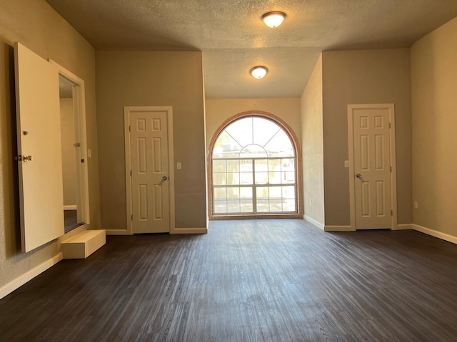 unfurnished room with dark wood-type flooring and a textured ceiling