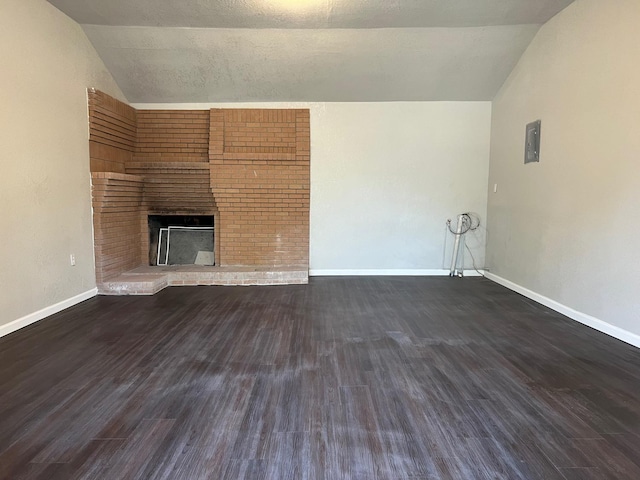 unfurnished living room with lofted ceiling, a brick fireplace, and dark hardwood / wood-style floors