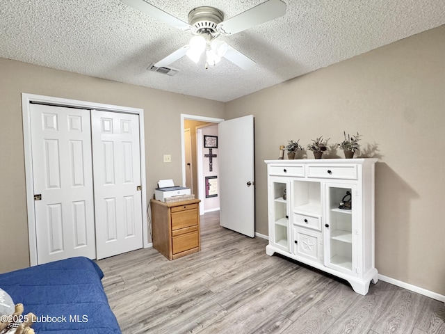 5226 92nd St, Lubbock, TX 79424 - bedroom with light wood-style flooring, a closet, a textured ceiling, ceiling fan, and baseboards