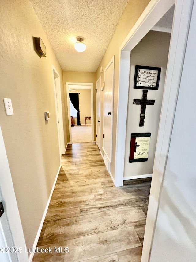 5226 92nd St, Lubbock, TX 79424 - hall featuring wood finished floors, a textured ceiling, and baseboards