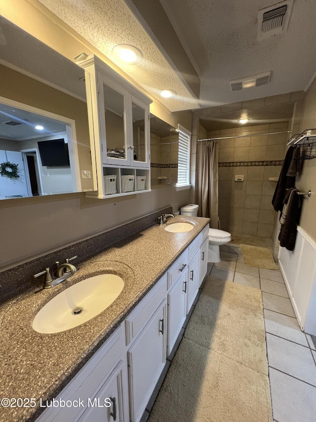 5226 92nd St, Lubbock, TX 79424 - full bathroom featuring a textured ceiling, a tile shower, toilet, double vanity, and tile patterned flooring