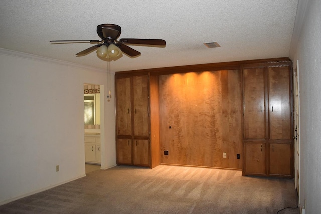 carpeted spare room with ornamental molding, ceiling fan, and a textured ceiling