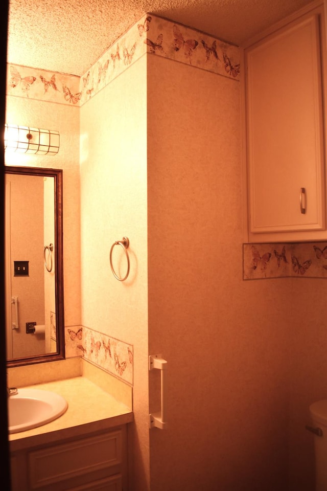 bathroom with vanity, toilet, and a textured ceiling