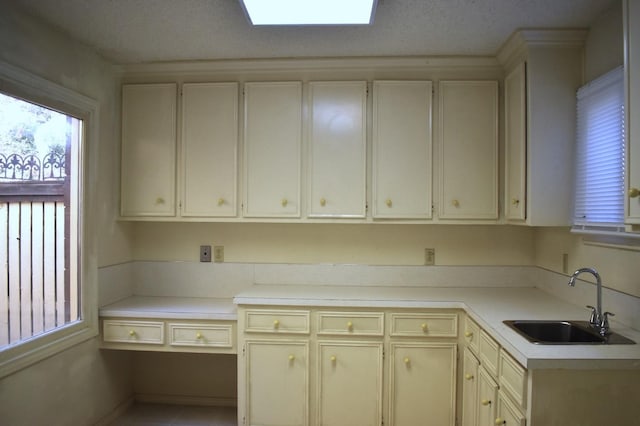 kitchen with sink, a textured ceiling, and cream cabinetry