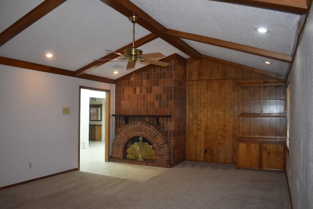 unfurnished living room featuring lofted ceiling with beams, light carpet, a textured ceiling, ceiling fan, and a fireplace