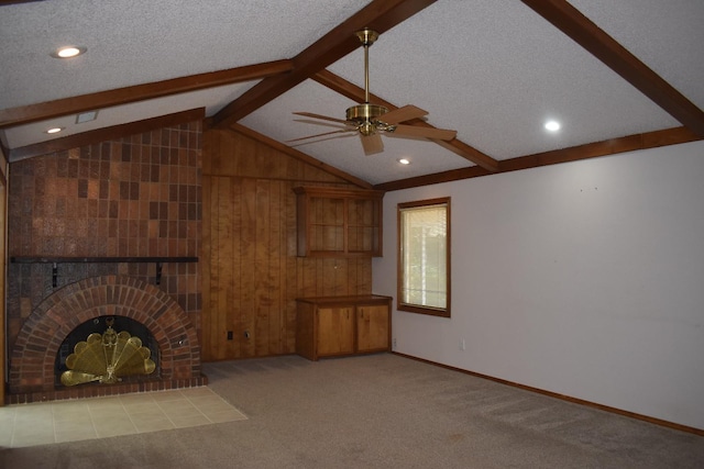 unfurnished living room featuring wooden walls, a fireplace, lofted ceiling with beams, light carpet, and a textured ceiling