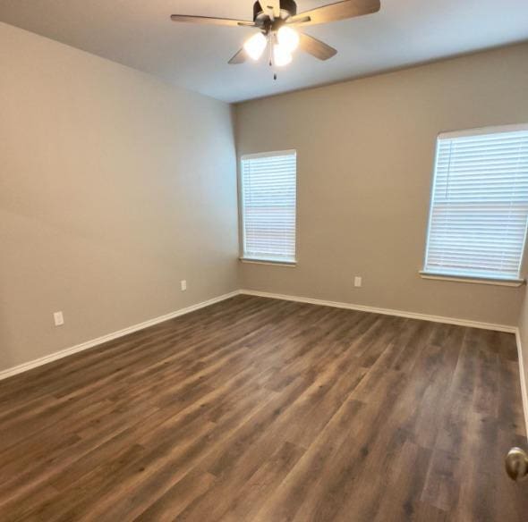 unfurnished room featuring dark wood-type flooring and ceiling fan