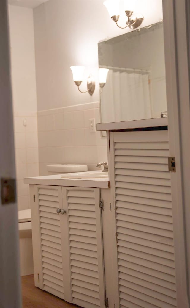 bathroom featuring tile walls, vanity, and toilet