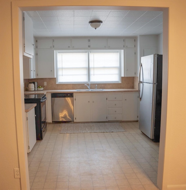 kitchen featuring tasteful backsplash, white cabinetry, appliances with stainless steel finishes, and sink