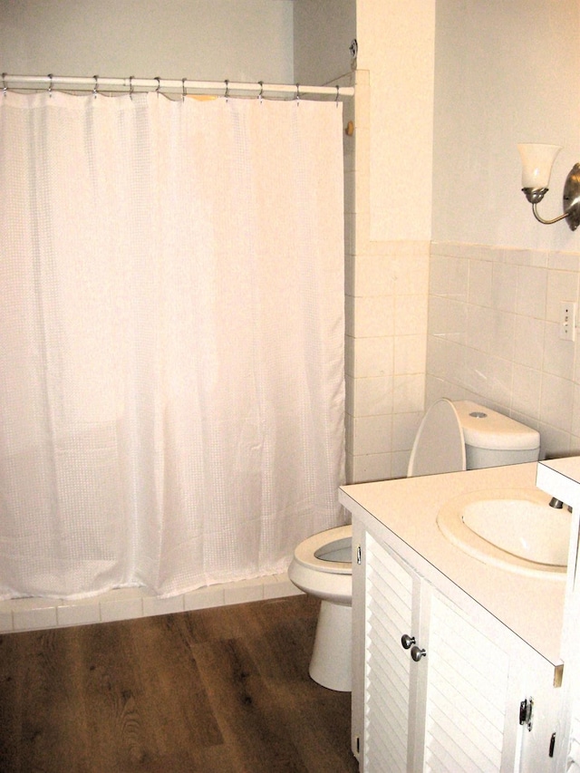 full bathroom featuring shower / bathtub combination with curtain, tile walls, vanity, wood-type flooring, and toilet