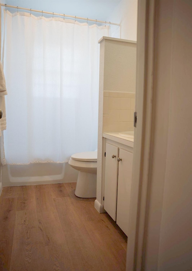 full bathroom featuring shower / bath combination with curtain, wood-type flooring, toilet, and vanity