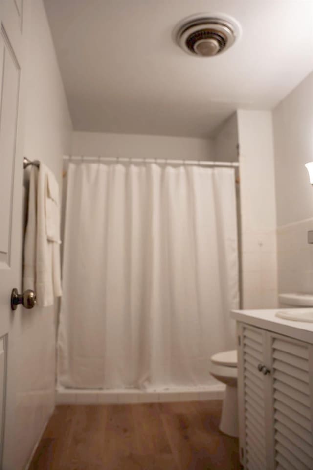 bathroom with vanity, hardwood / wood-style flooring, curtained shower, and toilet