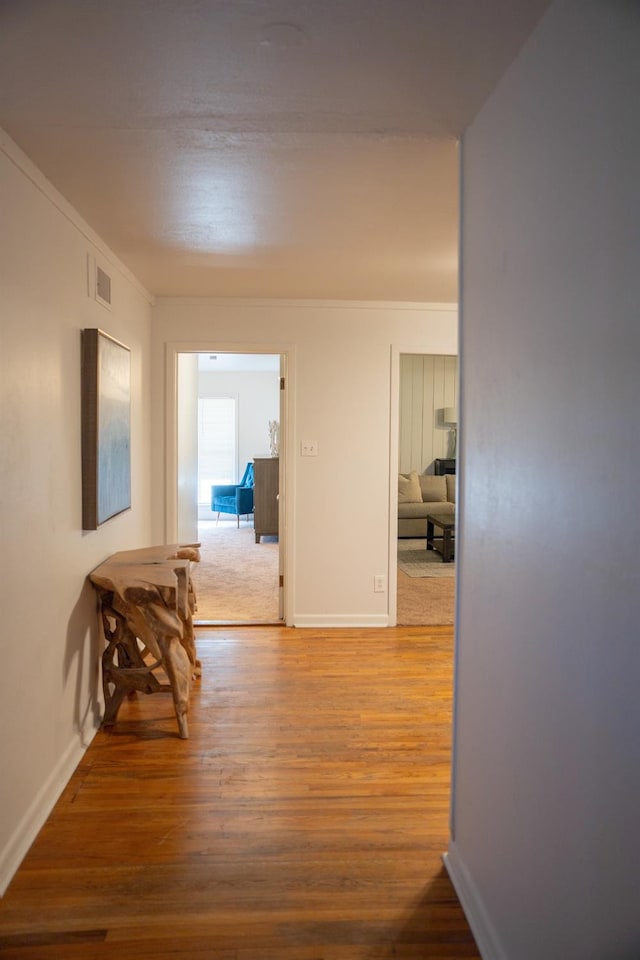 corridor with hardwood / wood-style flooring and crown molding