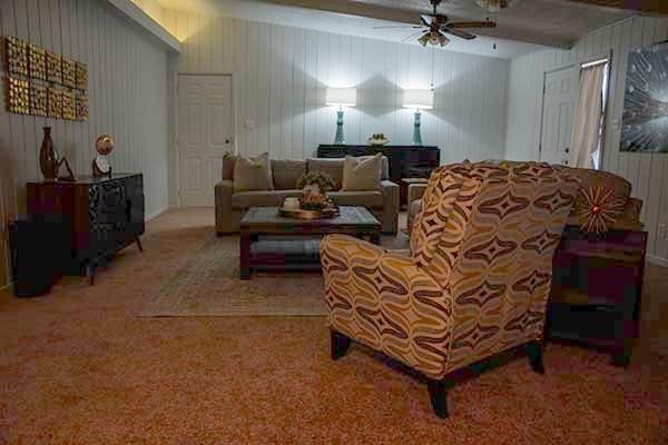 living room with beamed ceiling, ceiling fan, and carpet flooring