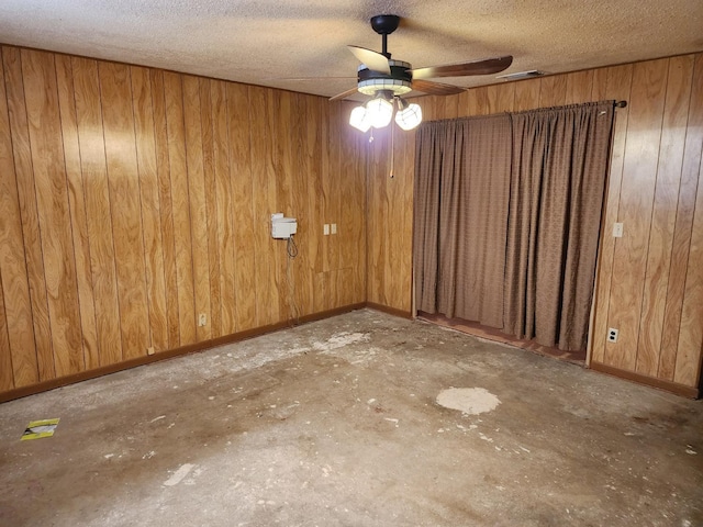 spare room with ceiling fan, a textured ceiling, and wooden walls