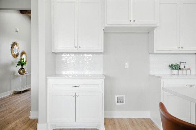1403 Durham Ave, Wolfforth, TX 79382 - kitchen featuring light countertops, light wood-type flooring, decorative backsplash, and white cabinetry