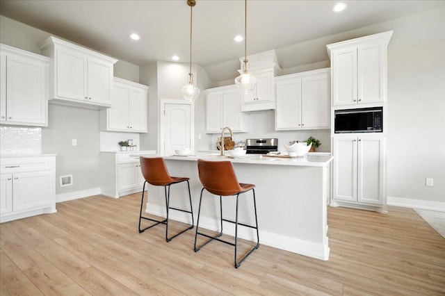 1403 Durham Ave, Wolfforth, TX 79382 - kitchen featuring built in microwave, stainless steel range with electric stovetop, decorative backsplash, white cabinetry, and light wood-style flooring