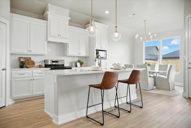 1403 Durham Ave, Wolfforth, TX 79382 - kitchen with stainless steel electric range, light wood finished floors, an island with sink, a breakfast bar, and recessed lighting
