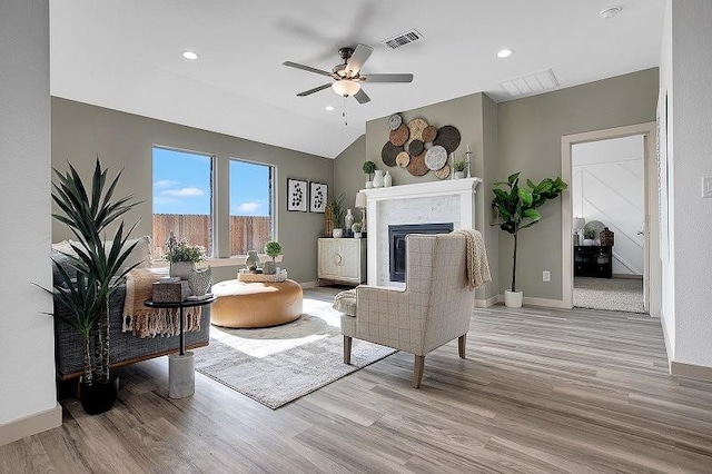 living room with ceiling fan, lofted ceiling, and light hardwood / wood-style floors