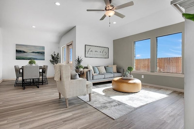 living room featuring ceiling fan, vaulted ceiling, and light hardwood / wood-style flooring