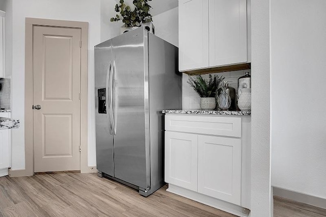 kitchen with white cabinetry, stainless steel refrigerator with ice dispenser, and decorative backsplash