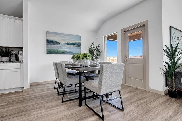 dining room with lofted ceiling and light hardwood / wood-style floors