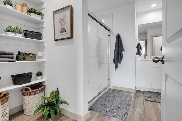 bathroom featuring walk in shower, vanity, and hardwood / wood-style floors