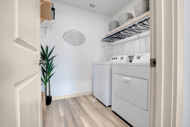 laundry room with light hardwood / wood-style floors and washing machine and dryer