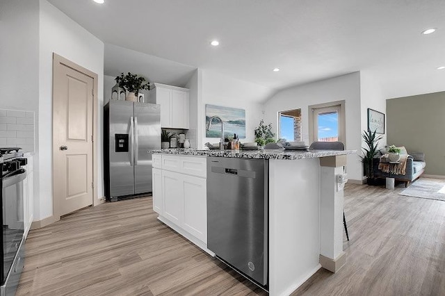 kitchen with white cabinetry, tasteful backsplash, a center island with sink, appliances with stainless steel finishes, and light stone countertops