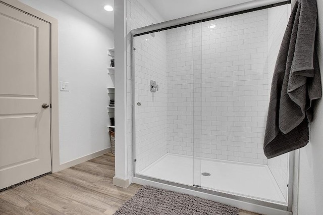 bathroom with hardwood / wood-style floors and a shower with shower door