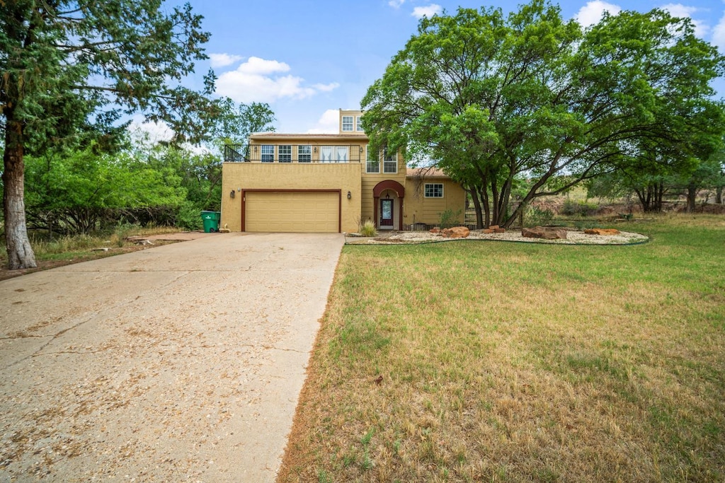 view of front of house with a garage, a front yard, and a balcony