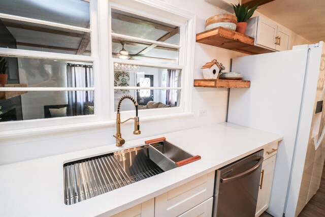 kitchen with sink, stainless steel dishwasher, white fridge with ice dispenser, and white cabinets