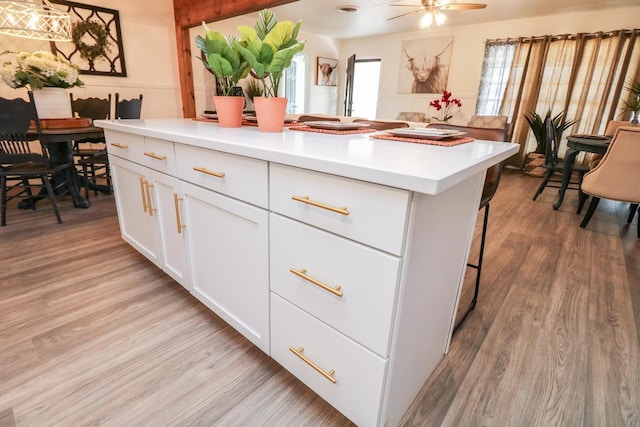 kitchen featuring white cabinetry, a kitchen island, ceiling fan, and light wood-type flooring