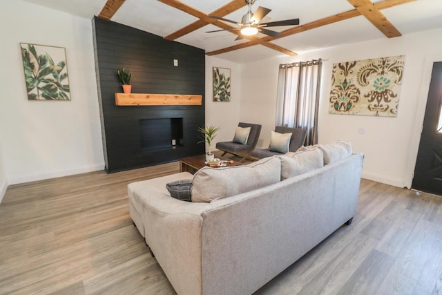 living room with beamed ceiling, ceiling fan, a fireplace, and light hardwood / wood-style flooring