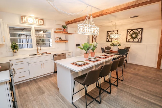 kitchen with pendant lighting, sink, a kitchen breakfast bar, stainless steel range, and white cabinets