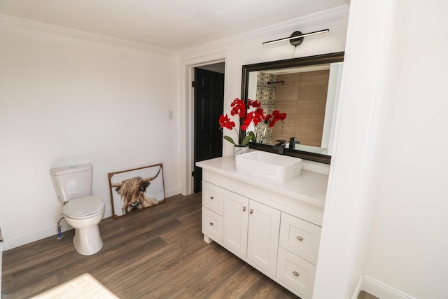 bathroom with wood-type flooring, ornamental molding, vanity, and toilet