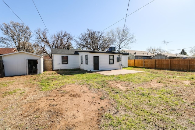 back of property with a yard, a patio area, and a storage unit