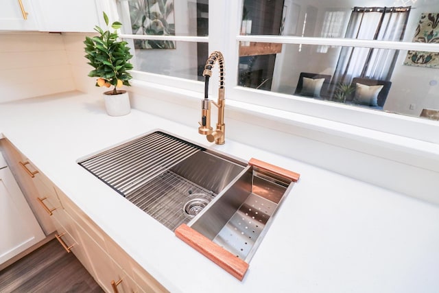 room details with dark hardwood / wood-style floors, sink, and white cabinets