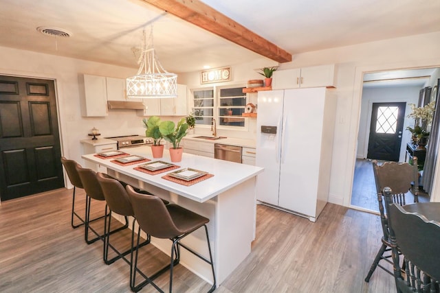 kitchen with a kitchen island, white cabinetry, appliances with stainless steel finishes, and a kitchen bar