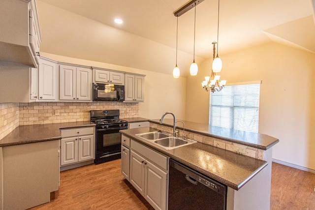 kitchen with vaulted ceiling, sink, backsplash, a kitchen island with sink, and black appliances