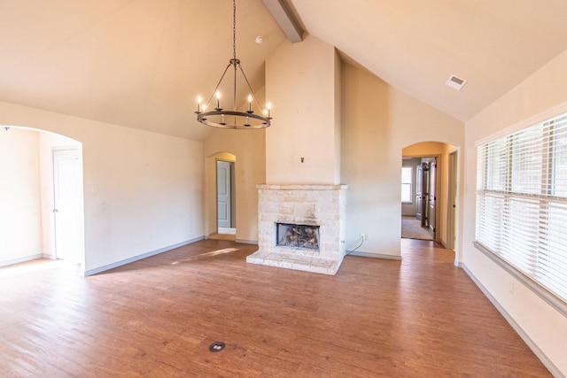 unfurnished living room with a stone fireplace, wood-type flooring, high vaulted ceiling, a notable chandelier, and beam ceiling