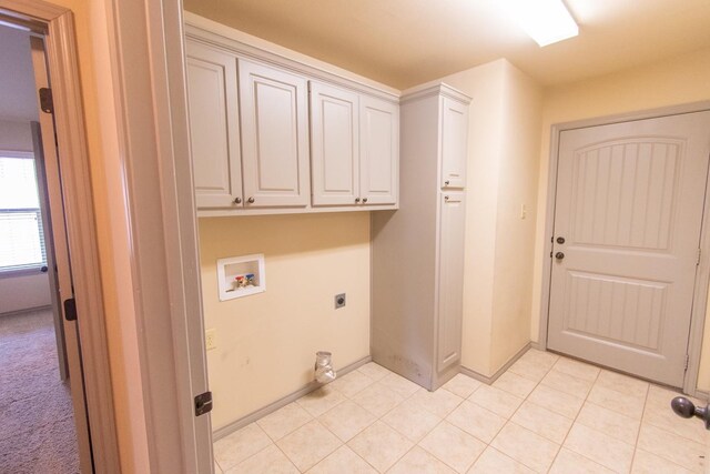 clothes washing area featuring cabinets, light tile patterned floors, hookup for a washing machine, and electric dryer hookup