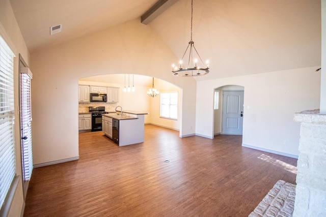 unfurnished living room featuring sink, an inviting chandelier, hardwood / wood-style floors, high vaulted ceiling, and beamed ceiling