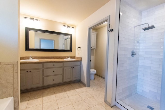 bathroom with tiled shower, vanity, toilet, and tile patterned flooring