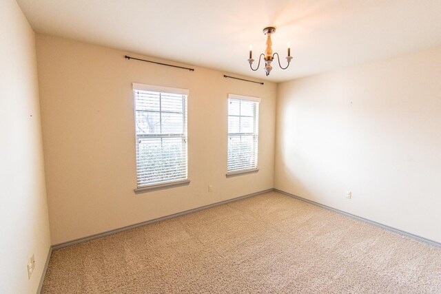 carpeted spare room featuring a chandelier