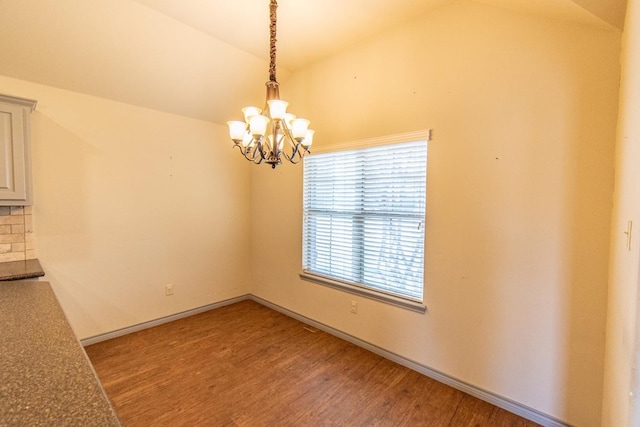 unfurnished dining area with lofted ceiling, light hardwood / wood-style floors, and an inviting chandelier