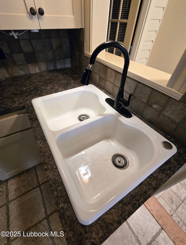 2413 25th St, Lubbock, TX 79411 - kitchen view of a sink, tasteful backsplash, dark countertops, and white cabinets