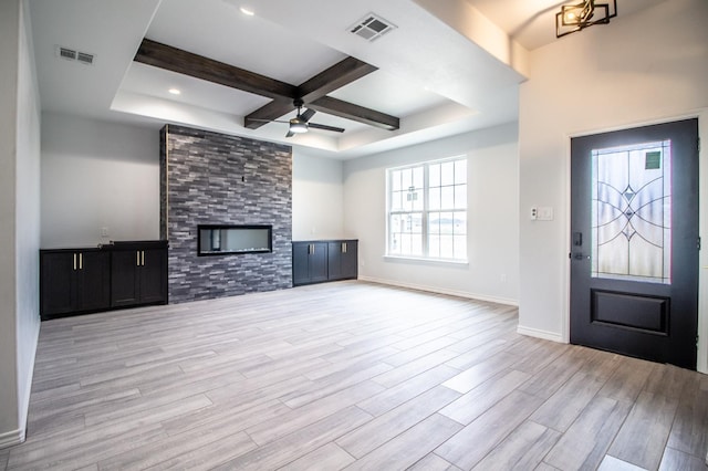 unfurnished living room with ceiling fan, coffered ceiling, a fireplace, beamed ceiling, and light wood-type flooring